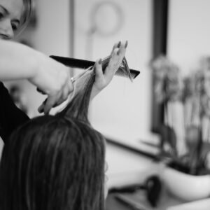 a woman cutting another woman's hair in a salon